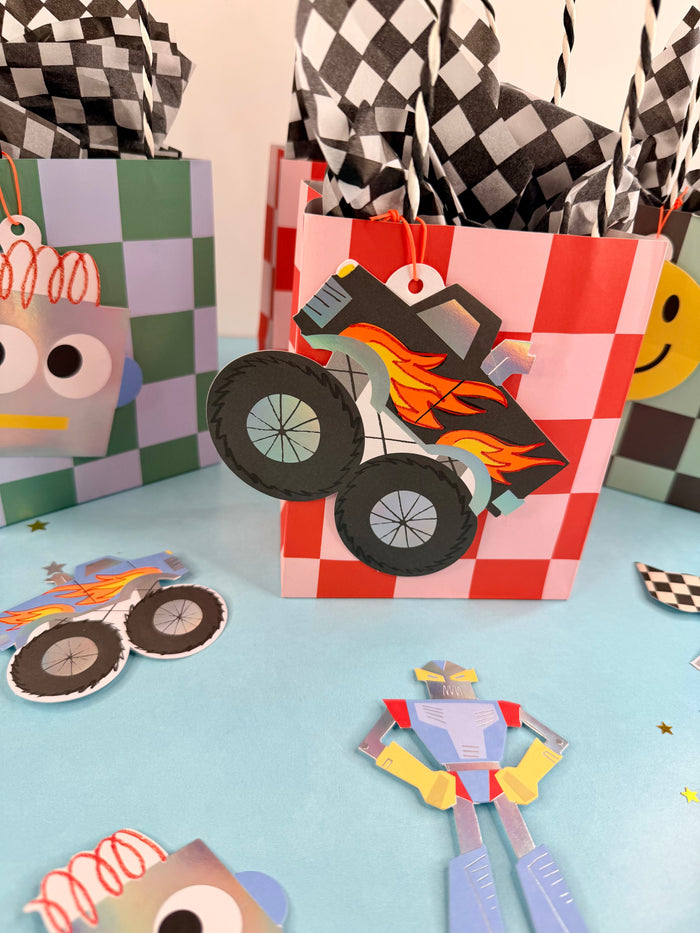 Colorful children's party favor boxes with monster truck design on a checkered background
