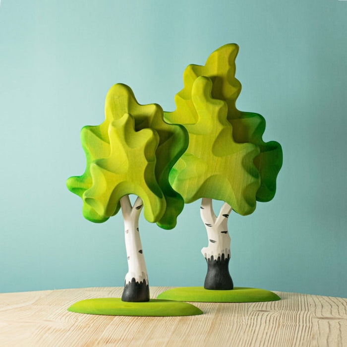 Colorful tree-shaped objects on a wooden surface with a light blue background