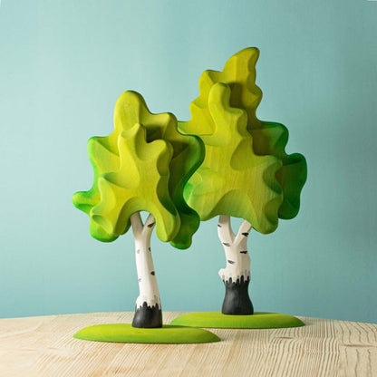Colorful tree-shaped objects on a wooden surface with a light blue background