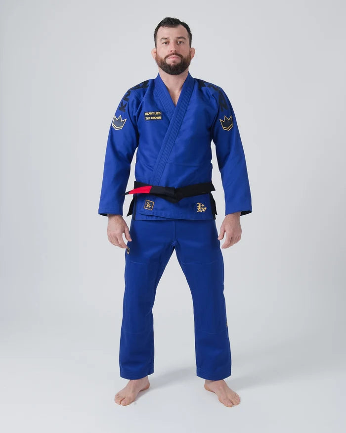 Kingz Comp 450 V6 Jiu Jitsu Gi Blue - Full Body Front View Male Athlete Blue Gi Black Kingz Shoulder Text Gold Crown Shoulder Patches Black Belt Heavy Lies The Crown Patch BJJ Gi Training [color:Blue]