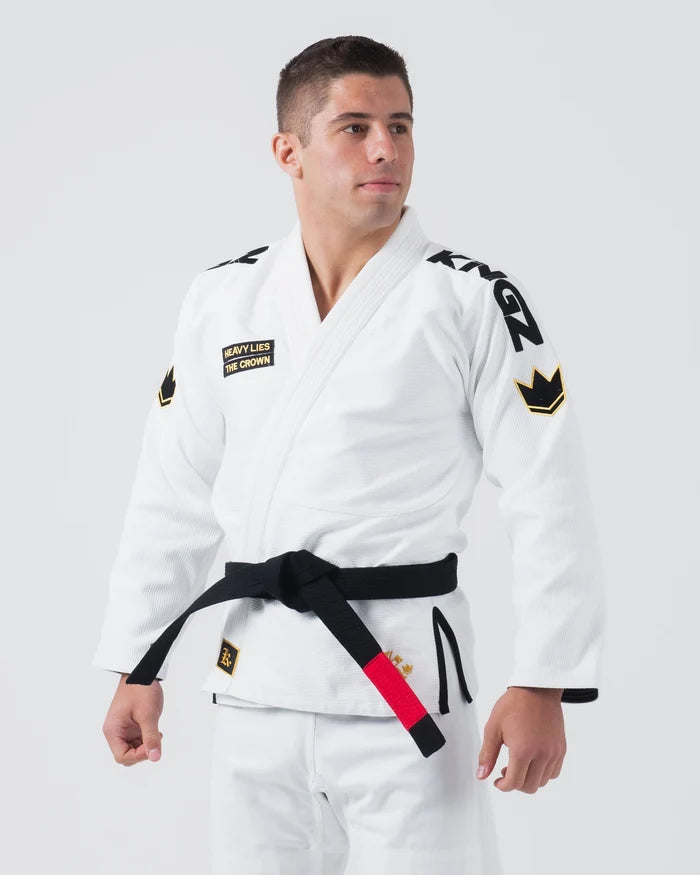 Kingz Comp 450 V6 Jiu Jitsu Gi - White - Three Quarter Front View Male Athlete Black Belt Shoulder Logos Crown Badge Chest Patch Heavy Lies The Crown Text BJJ Gi Training [color:White]