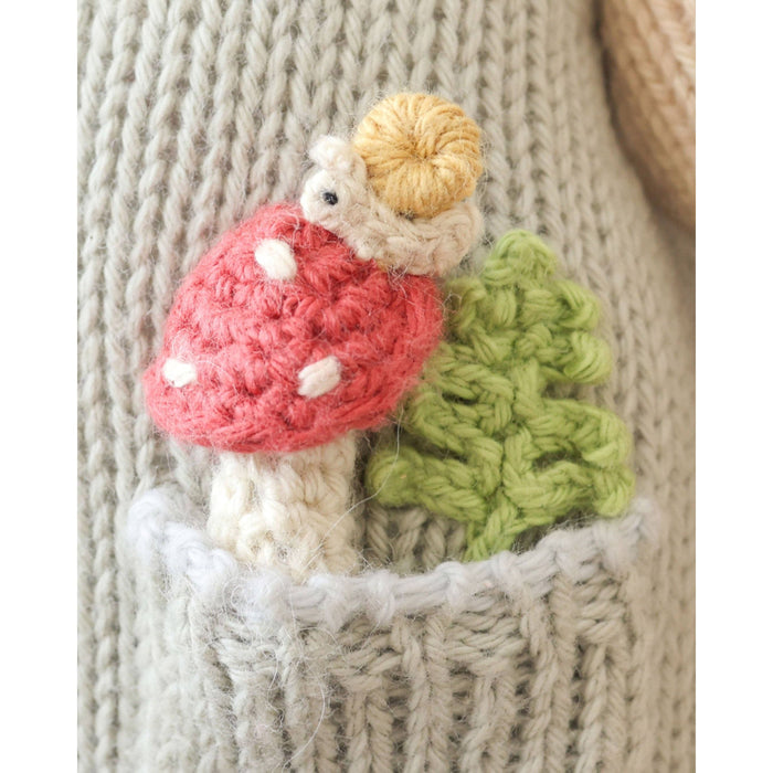 Knitted mushroom with a small creature on top of a textured fabric background
