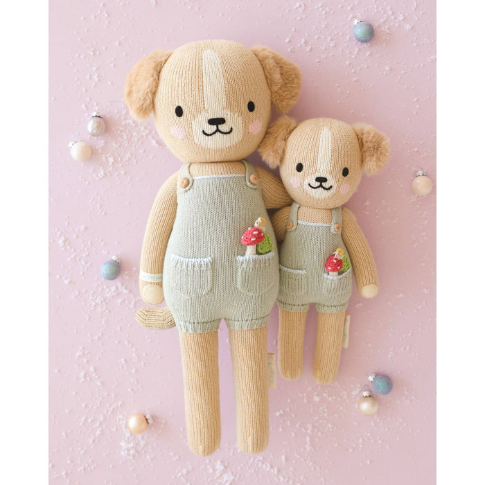 Two knitted teddy bears in overalls on a pink background
