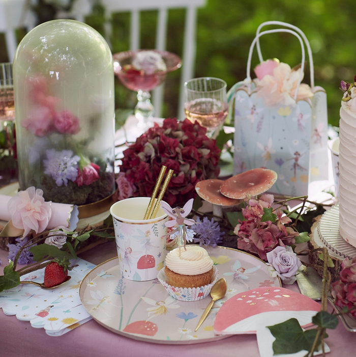 Decorative table setting with flowers, a cupcake, and fairy-themed elements.