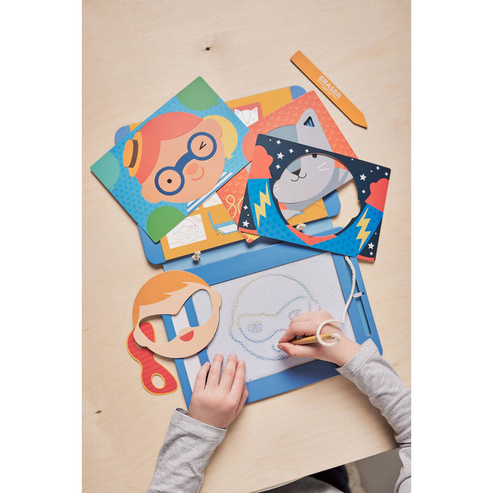 Child drawing with colorful paper cutouts of faces on a wooden table