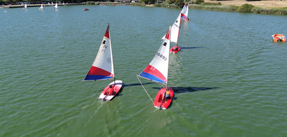 Red and white sailing boats on Piddinghoe lake