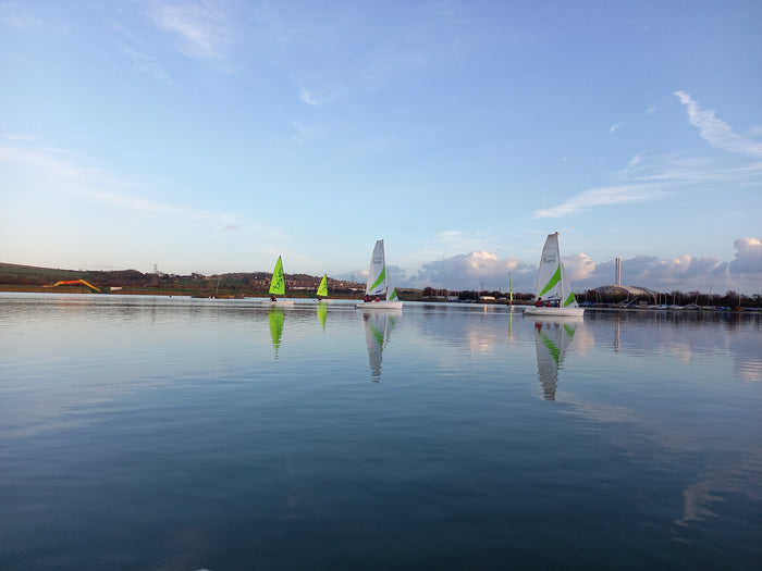 A serene view of several sailboats on water with a clear blue sky and calm waves.