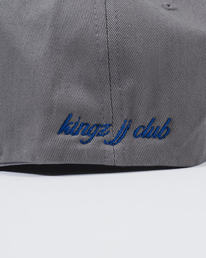 Kingz Jiu Jitsu Club Snapback Grey - Close-Up Detail View Blue Embroidered "kingz jiu club" Text Grey Fabric Texture BJJ Hat [color:Grey]