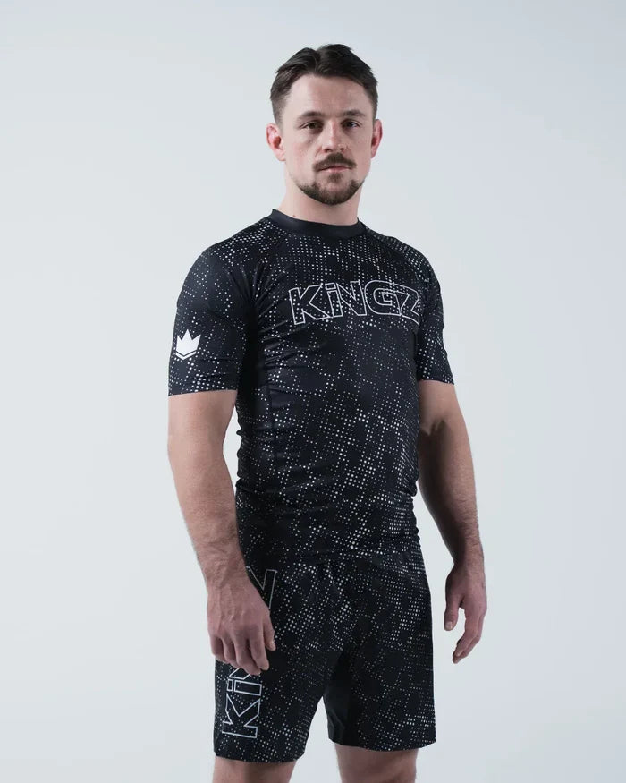 Kingz Acid Wash Rashguard Black - Full Body 3/4 Angled Front View Male Athlete Short Sleeve Large KINGZ White Outline Text Crown Logo Acid Wash Dot Pattern Matching Shorts [color:Black/Acid]