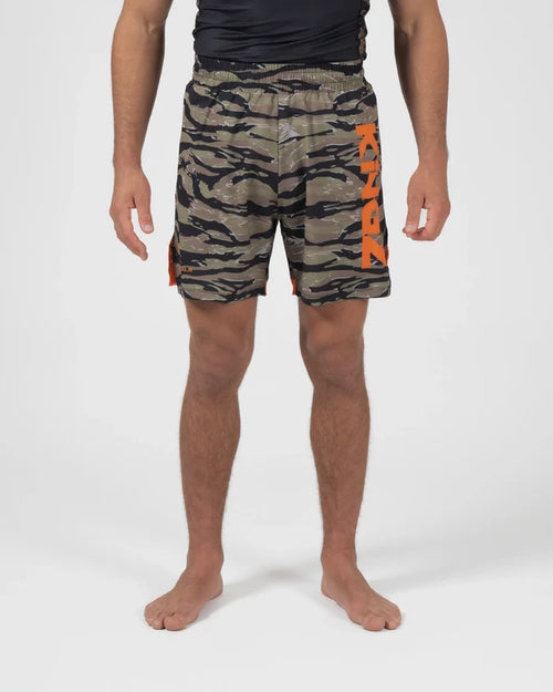 Kingz Always Hunting Shorts Green Camo - Full Body Front View Male Athlete Olive Army Green Tiger Camo Pattern KINGZ Bold Orange Text Left Leg Orange Side Accent Panels Inner Compression Shorts Orange Trim Competition Cut Men's Grappling Shorts No-Gi BJJ [color:Green Camo]