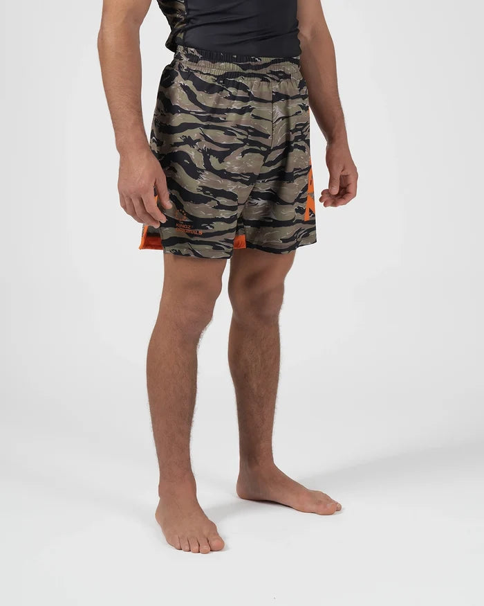 Kingz Always Hunting Shorts Green Camo - Upper Body Front View Male Athlete Tiger Camo Pattern Orange Bold Side Panel Right Side KINGZ Badge Orange Accent Stripe Competition Cut Men's Grappling Shorts No-Gi BJJ [color:Green Camo]