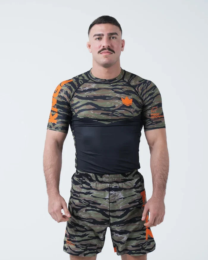 Kingz Always Hunting Rashguard Green Camo - Full Body Front View Male Athlete Short Sleeve Tiger Camo Pattern Orange Crown Logo Orange Accents Matching Camo Shorts [color:Green Camo]