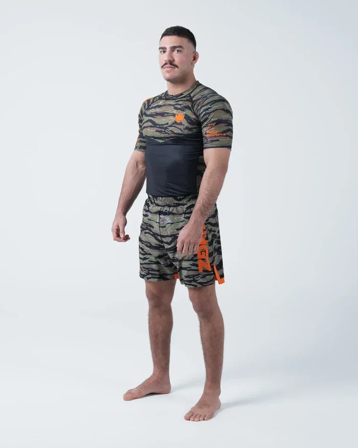 Kingz Always Hunting Rashguard Green Camo - Full Body Front View Barefoot Male Athlete Short Sleeve Tiger Camo Orange Crown Logo KINGZ Performance Badge Camo Shorts [color:Green Camo]