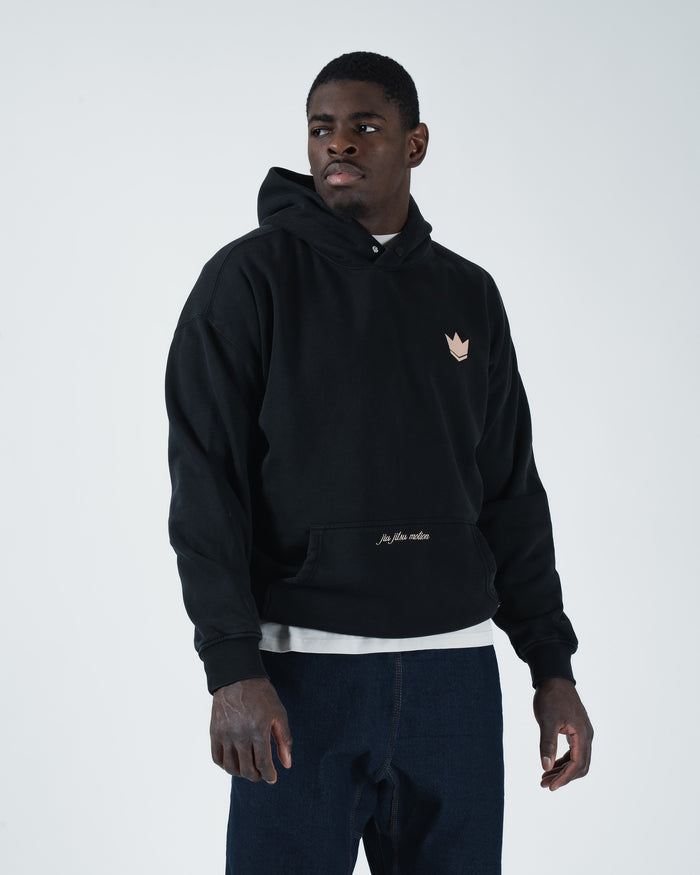 Black BJJ hoodie front pose on adult male model displaying boxy dual panel silhouette and crown emblem [color:Black]