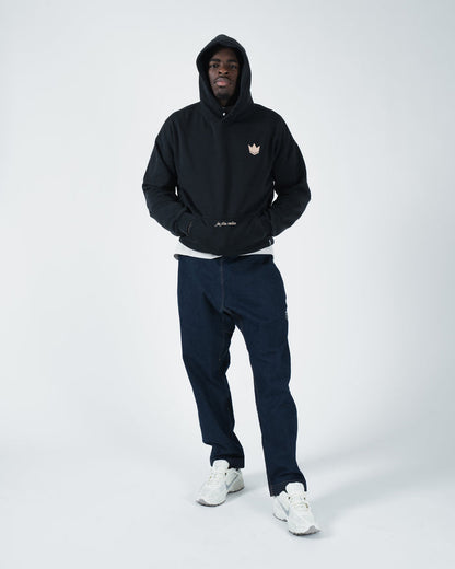 Black BJJ hoodie front view on adult male model with tan crown emblem and layered casual training look [color:Black]