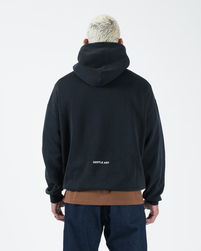 Black BJJ hoodie rear view on adult male model displaying Gentle Art back text and ribbed cuffs [color:Black]