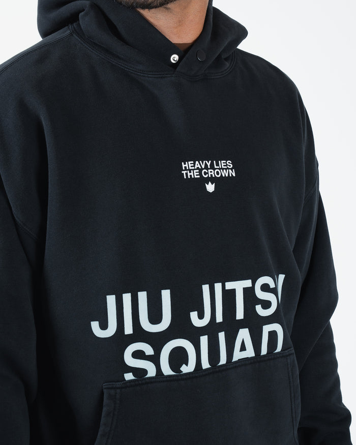 Black BJJ hoodie closeup detail of Heavy Lies The Crown crown logo and Jiu Jitsu Squad chest print [color:Black]
