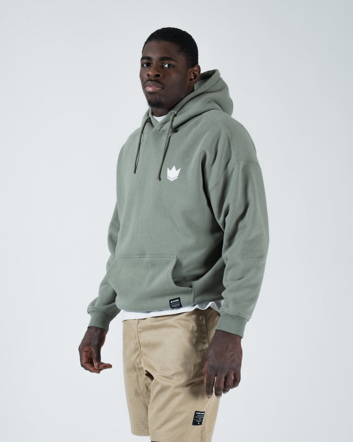 Dark forest green BJJ hoodie front three-quarter view on adult male model showing crown logo and box fit