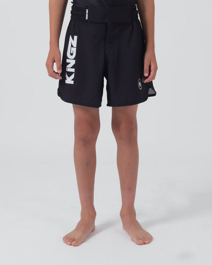 Kingz Kore V2 Youth Shorts Black - Full Body Front View Teen Boy Athlete Solid Black Bold Vertical KINGZ White Text Left Leg Circular Crown Badge Right Competition Cut Kids Grappling Shorts No-Gi BJJ Kore Collection [color:Black]