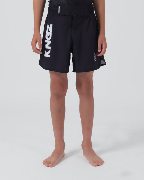 Kingz Kore V2 Youth Shorts Black - Full Body Front View Teen Boy Athlete Solid Black Bold Vertical KINGZ White Text Left Leg Circular Crown Badge Right Competition Cut Kids Grappling Shorts No-Gi BJJ Kore Collection [color:Black]