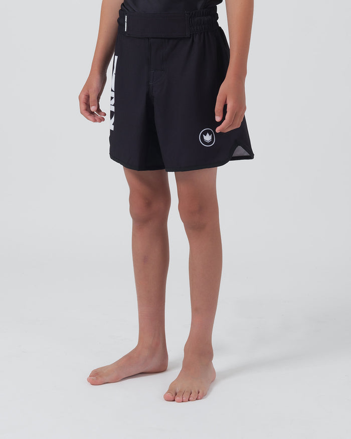 Kingz Kore V2 Youth Shorts Black - Full Body Right Side Profile Teen Boy Athlete Solid Black Crown Badge Right Thigh KINGZ Bold Text Left Leg Visible Kids Grappling Shorts No-Gi BJJ Kore Collection [color:Black]