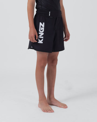 Kingz Kore V2 Youth Shorts Black - Full Body Left Side Profile Teen Boy Athlete KINGZ Bold White Vertical Text Left Leg Side Split Visible Kids Grappling Shorts No-Gi BJJ Kore Collection [color:Black]