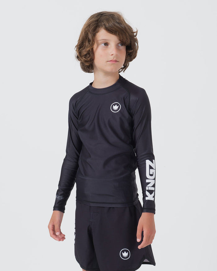 Kingz Kore V2 Youth L/S Rashguard Navy Black - Full Body 3/4 Front View Teen Boy Athlete Long Sleeve Navy Blue Crown Logo Circle Chest KINGZ White Vertical Sleeve Text Matching Navy Shorts Crown Logo Hem Kids BJJ Minimal [color:Black]