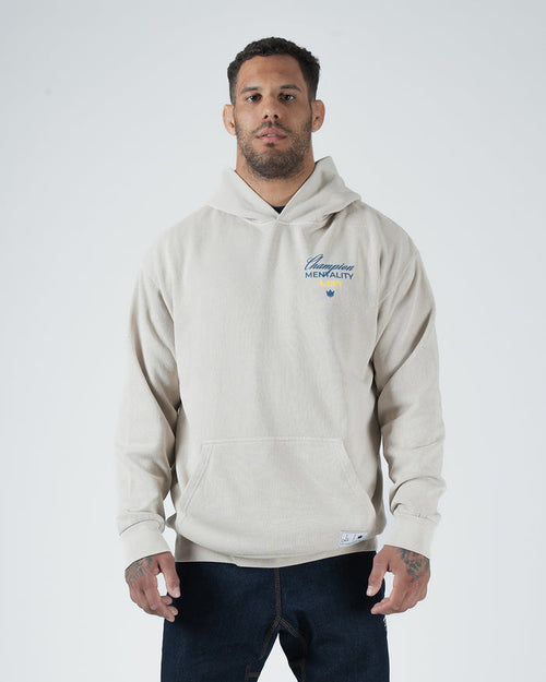 Tan BJJ Champion hoodie front view on adult male model showing blue Champion Mentality chest script [color:French Oak]
