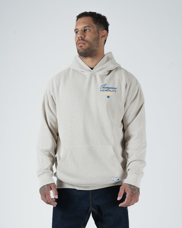 Tan BJJ Champion hoodie front three-quarter view on adult male model with Champion Mentality chest logo [color:French Oak]