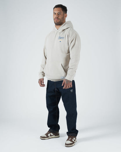 Tan BJJ Champion hoodie full body lifestyle shot with adult male model in dark jeans and casual sneakers [color:French Oak]