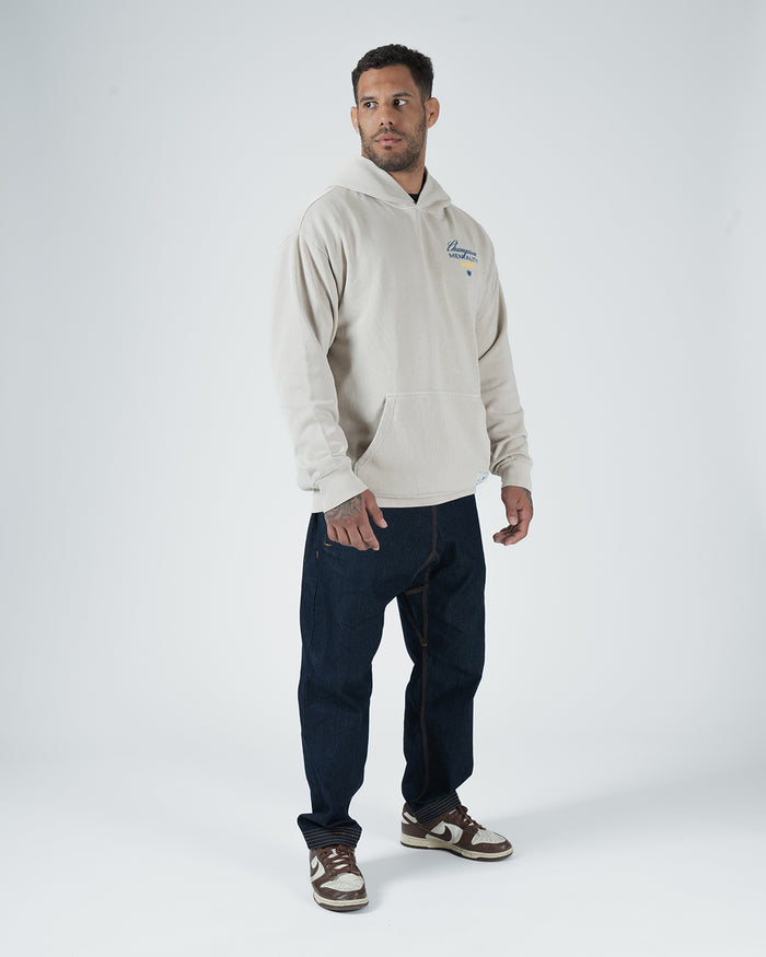 Tan BJJ Champion hoodie full body back lifestyle shot with adult male model showing Champion Mentality art [color:French Oak]