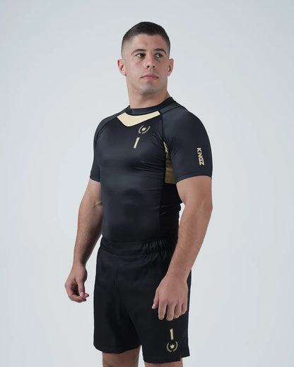 Kingz Player Special Limited Edition Rashguard Black Gold - Full Body Back View Right Side Barefoot Male Athlete Gold Center Back Panel Winged Crown Logo Black Shorts KINGZ Text [color:Black]