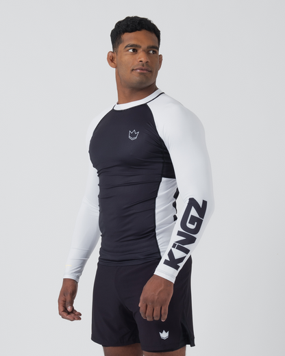 Kingz Ranked Performance V2 L/S Rashguard Navy White - Full Body 3/4 Front Right Side View Male Athlete Long Sleeve Navy Body White Right Sleeve KINGZ Bold Black Text Sleeve Crown Logo Chest Navy Shorts Performance Fit [color:White]