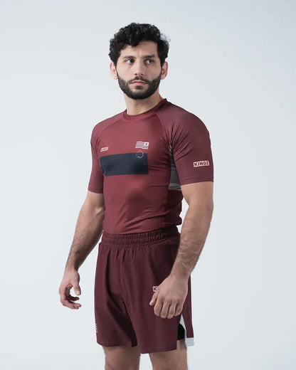 Kingz Trooper Rashguard Maroon - Full Body 3/4 Angled Front View Male Athlete Short Sleeve KINGZ Logo Black Chest Band Flag Patch Right Side View [color:Maroon]