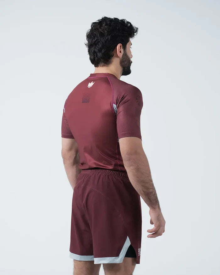Kingz Trooper Rashguard Maroon - Full Body 3/4 Back View Left Side Male Athlete Short Sleeve Crown Logo Left Shoulder Maroon Shorts Gray White Trim [color:Maroon]