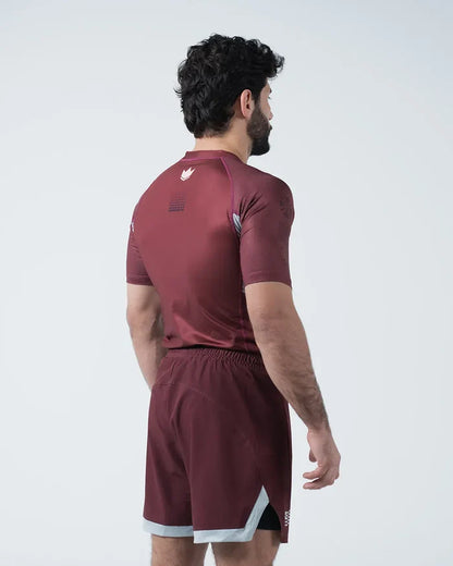 Kingz Trooper Rashguard Maroon - Full Body 3/4 Back View Left Side Male Athlete Short Sleeve Crown Logo Left Shoulder Maroon Shorts Gray White Trim [color:Maroon]