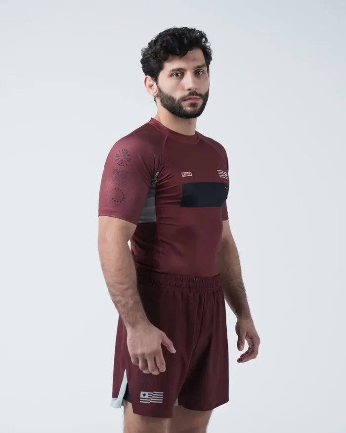 Kingz Trooper Rashguard Maroon - Full Body Front View Male Athlete Short Sleeve KINGZ Logo Black Chest Band Flag Patch Sunburst Design Maroon Shorts [color:Maroon]