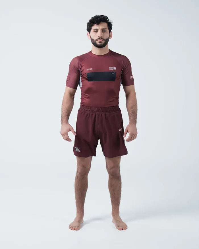 Kingz Trooper Rashguard Maroon - Full Body Straight Front View Male Athlete Barefoot Short Sleeve KINGZ Logo Black Chest Band Flag Patches Maroon Shorts [color:Maroon]
