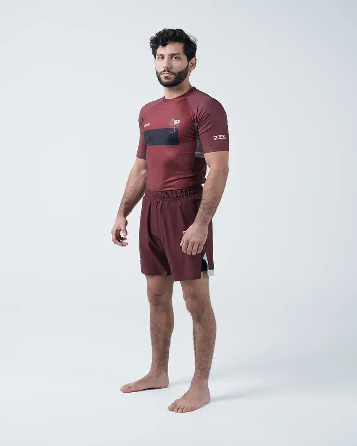 Kingz Trooper Rashguard Maroon - Full Body 3/4 Angled Front View Male Athlete Barefoot Short Sleeve KINGZ Logo Black Chest Band Flag Patches Maroon Shorts [color:Maroon]