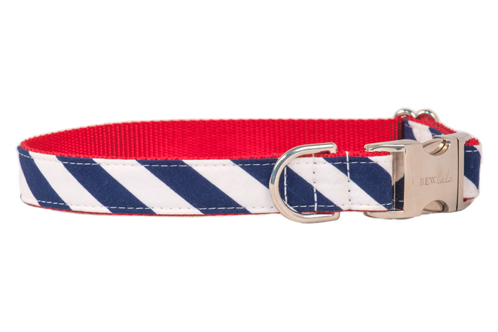Stylish dog collar with a nautical or Americana vibe, showcasing diagonal navy and white stripes on cotton fabric, paired with a vibrant red inner webbing. The collar is finished with sleek silver-tone hardware, including a durable D-ring and engraved clasp for a polished, functional look.