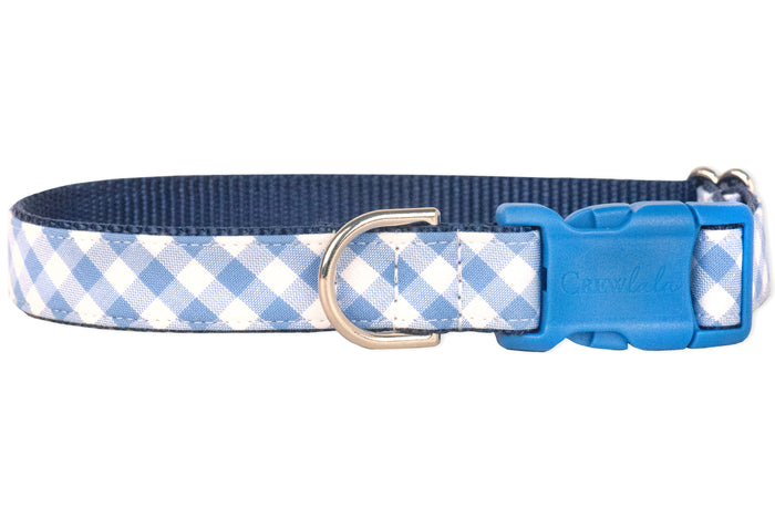 Dog collar with a classic periwinkle and white plaid pattern, layered over durable navy blue webbing. The design includes reinforced stitching, a blue buckle and a metal D-ring for secure leash connection, blending charm with everyday functionality.