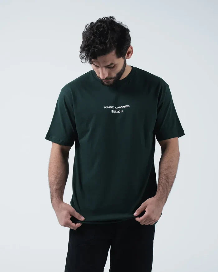 Kingz Solo Tee - Front Looking Down Pose - Kingz Kimonos Est 2011 Chest Text Clearly Visible - Dark Green BJJ