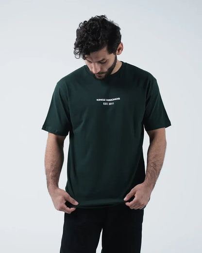 Kingz Solo Tee - Front Looking Down Pose - Kingz Kimonos Est 2011 Chest Text Clearly Visible - Dark Green BJJ