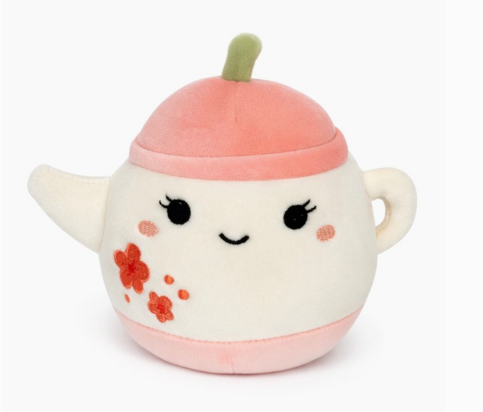Plush toy resembling a character with a pink hat and floral design on a white background