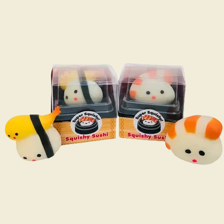 Two packaged and two unpackaged squishy sushi toys on a plain white background. The set includes a yellow and white sushi piece with a black band, a white and orange striped sushi piece, and their clear plastic boxes with printed labels reading 'Super Squishy Squishy Sushi'.